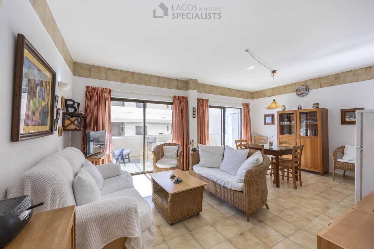 Spacious living and dining area with wicker furniture and sliding doors to terrace in Iberlagos apartment, Lagos