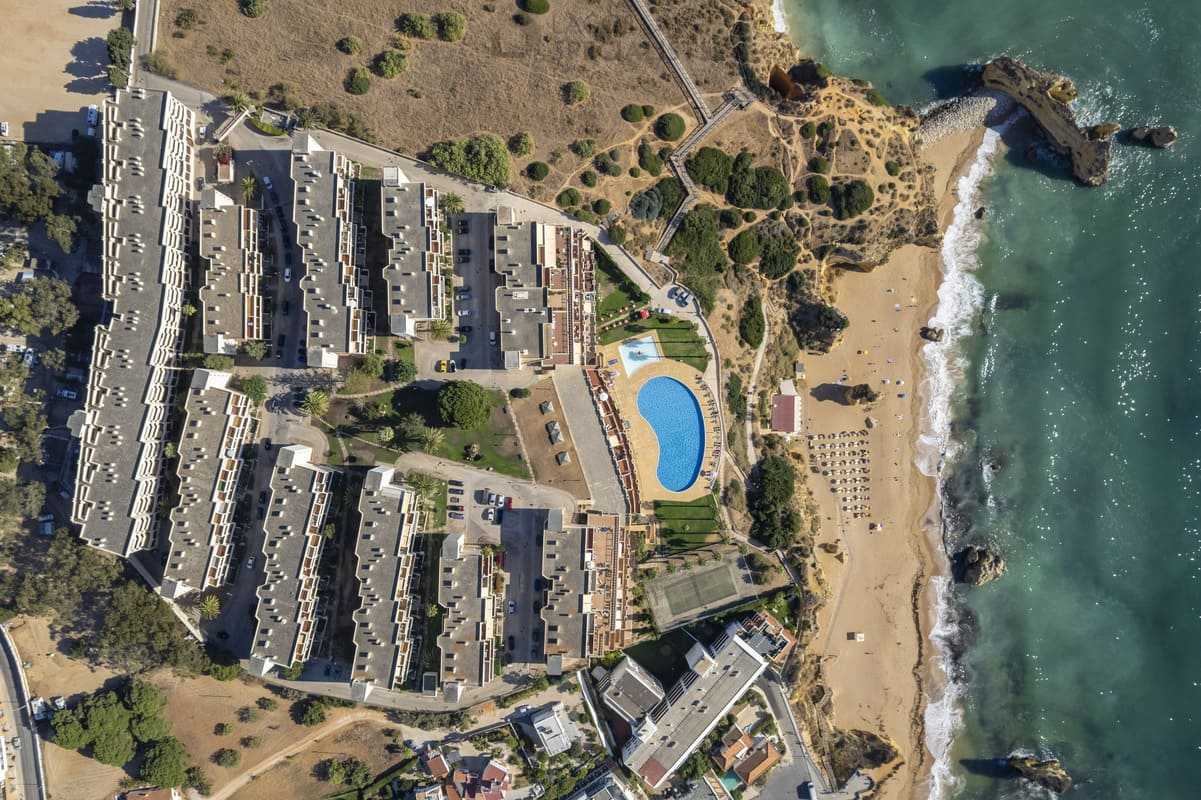 Aerial top-down view of Iberlagos resort, pool and Dona Ana Beach with boardwalks and cliffs in Lagos Algarve