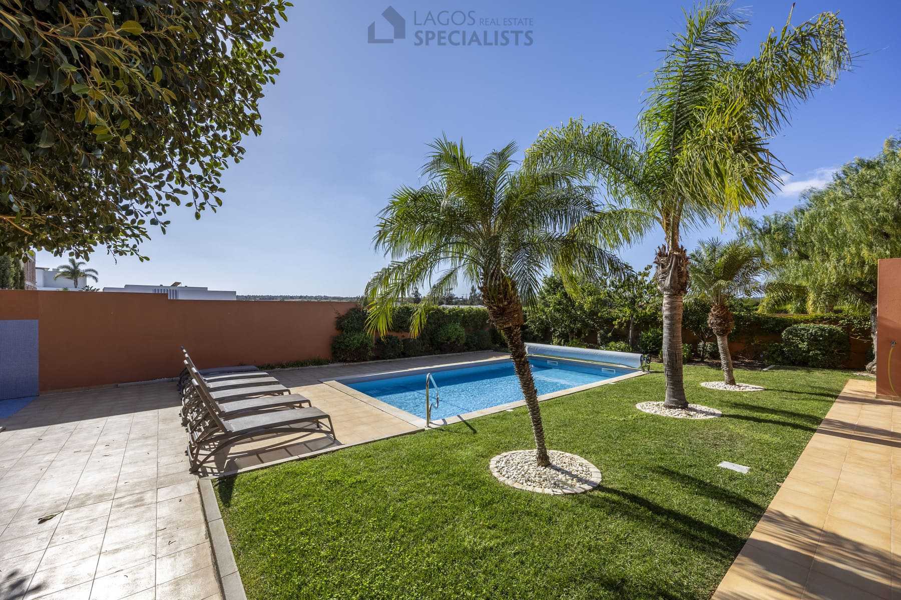 Sun loungers and poolside area surrounded by greenery, Lagos home