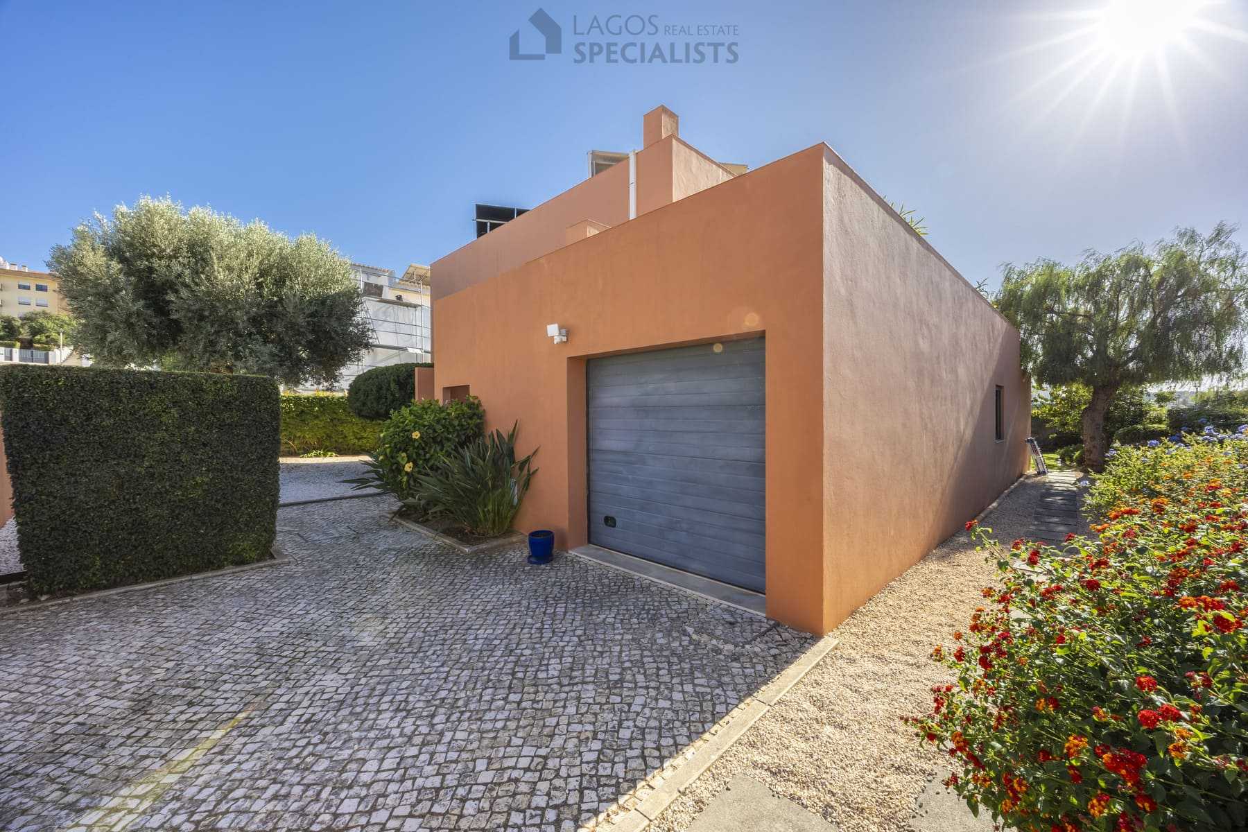 Villa entrance and driveway with garage, cobblestone path and garden