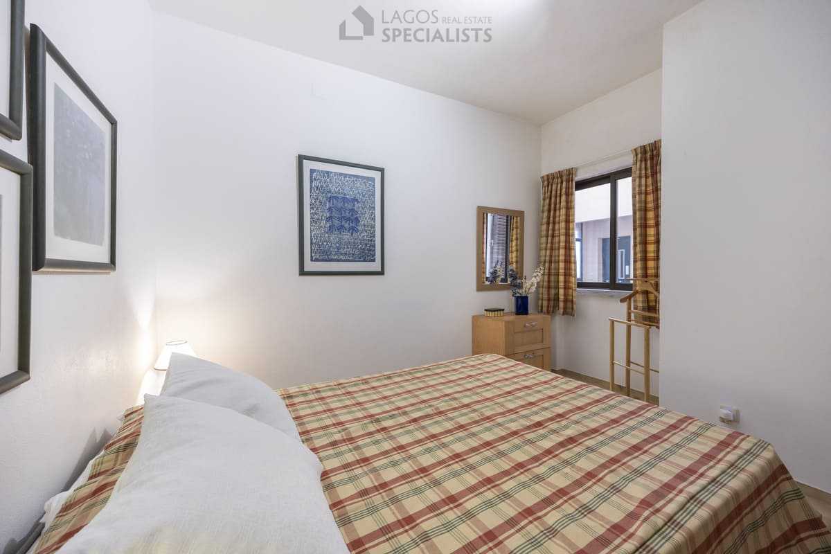 Double bedroom with window, dresser and checked curtains in an Iberlagos apartment near Dona Ana Beach