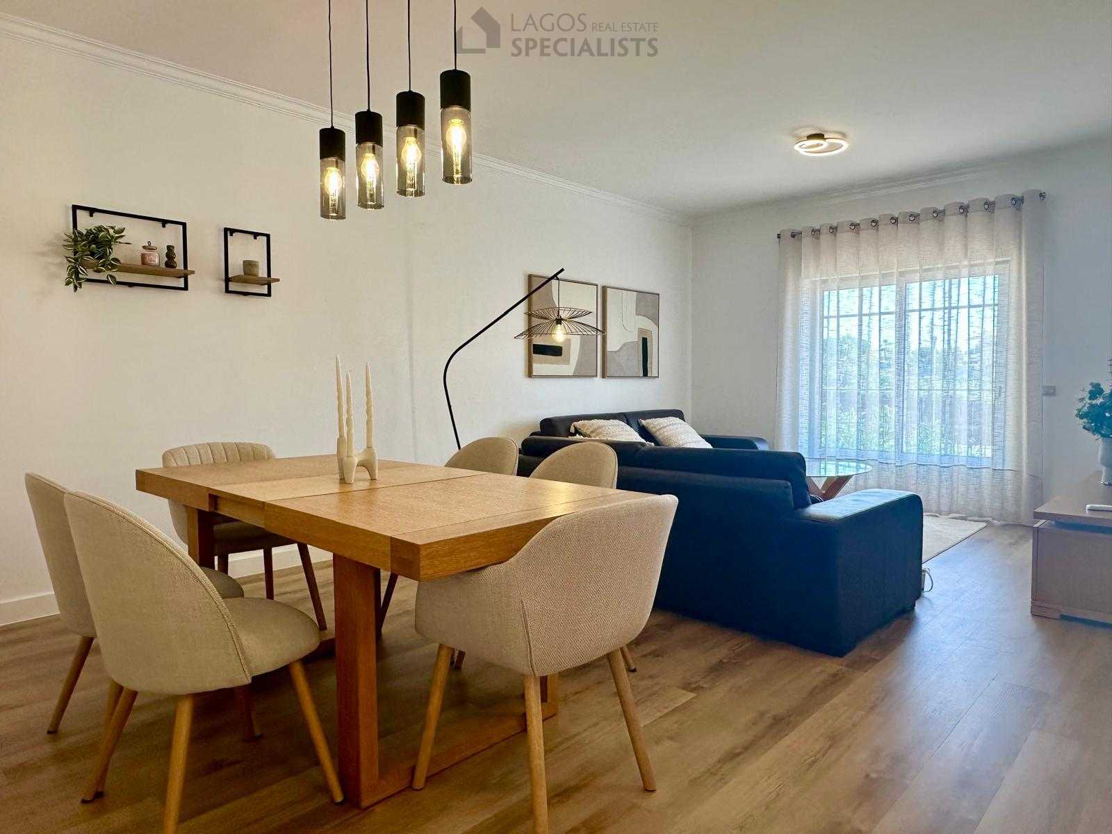View of living room from dining area showing warm wooden tones and modern lighting