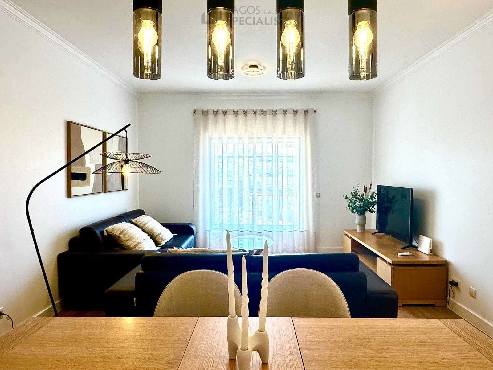 Contemporary living room with TV unit, black sofas, and artistic ceiling lamp