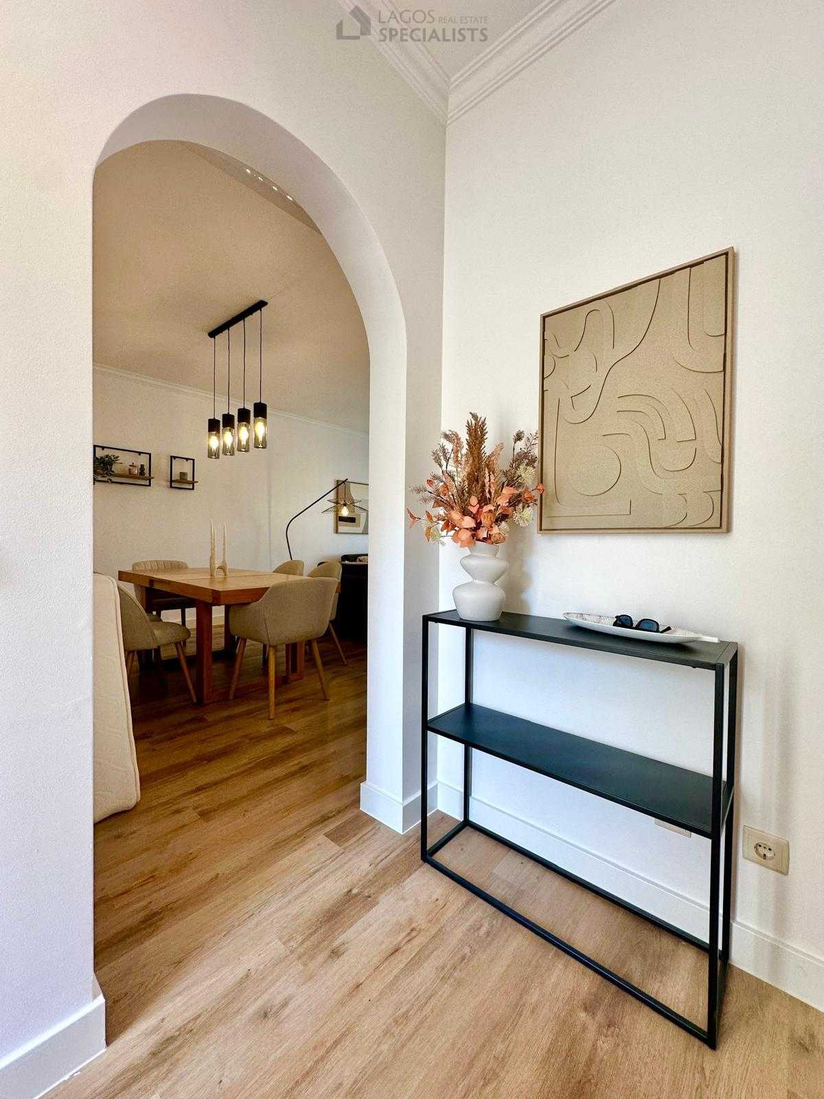 Entryway with arched opening leading to dining area, wooden floors, and decorative console