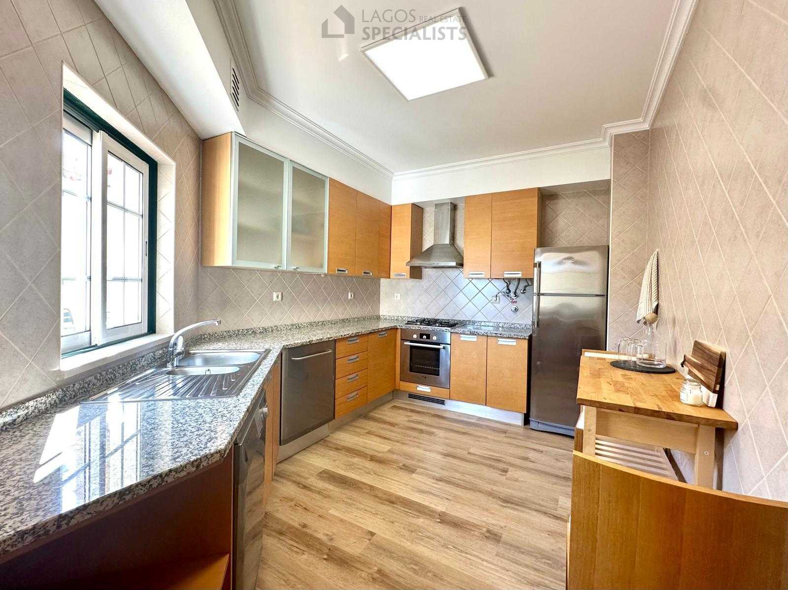 Bright kitchen with large window and modern fittings overlooking condominium terrace