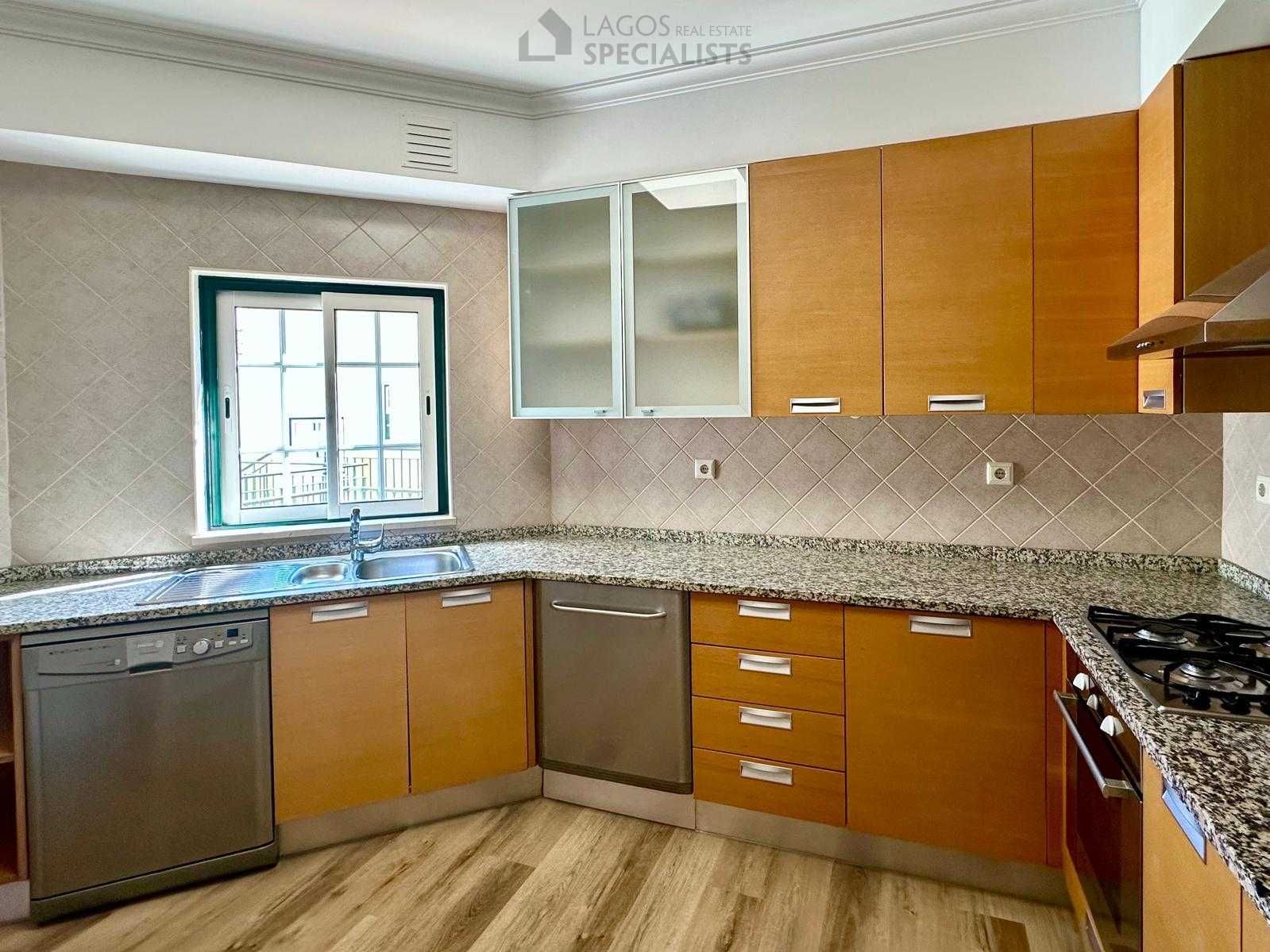 Spacious kitchen with wood cabinetry, granite countertops, and tiled walls