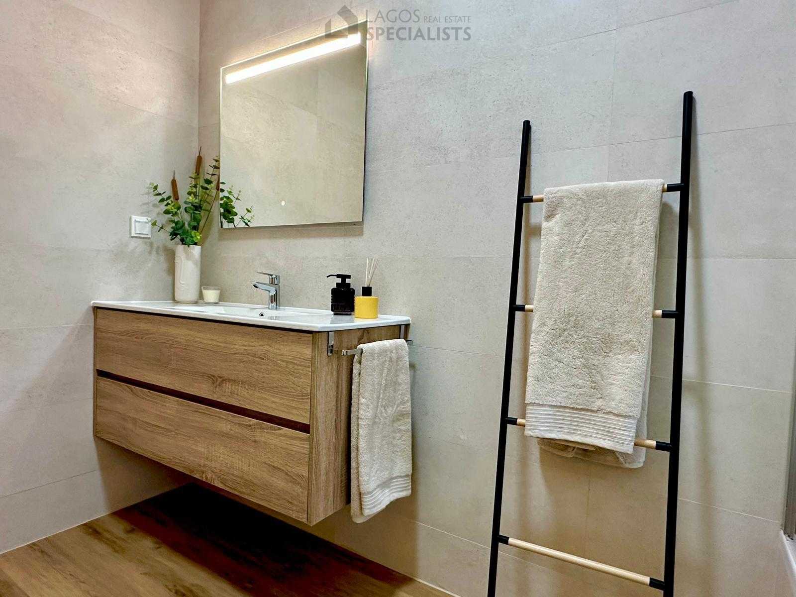 Renovated bathroom with wood-style vanity and decorative towel ladder