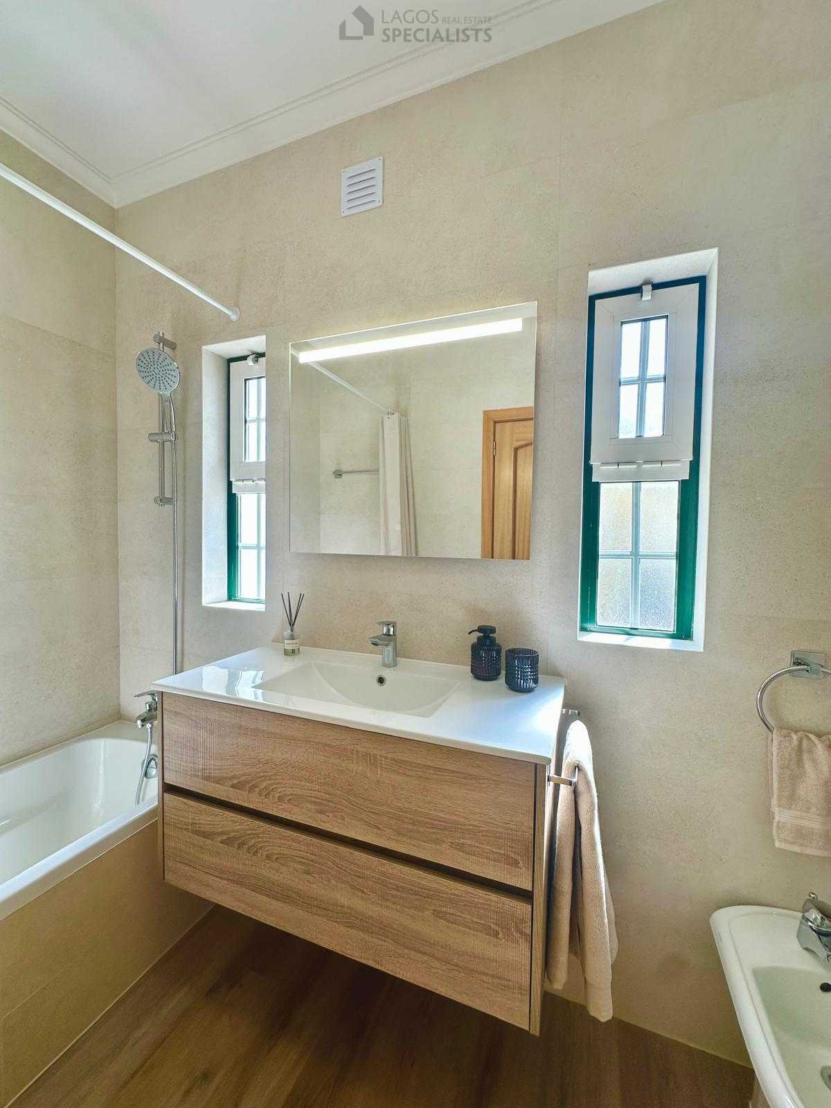 Renovated bathroom with wood-style vanity and decorative towel ladder