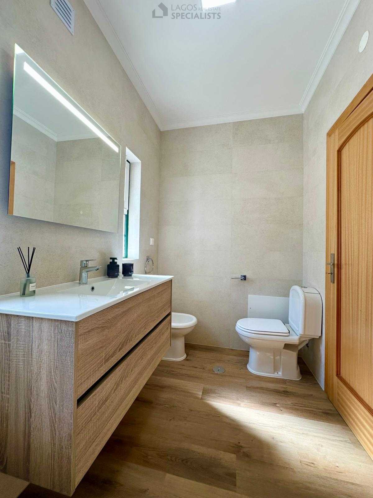 Renovated bathroom with wood-style vanity and decorative towel ladder
