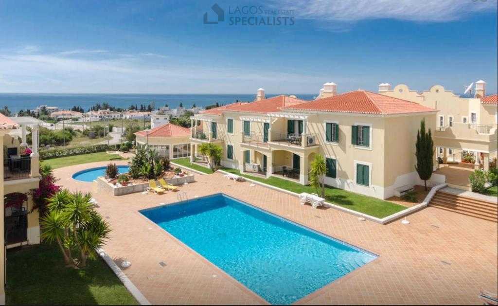 Large communal pool surrounded by sun loungers and gardens with sea views in the Algarve