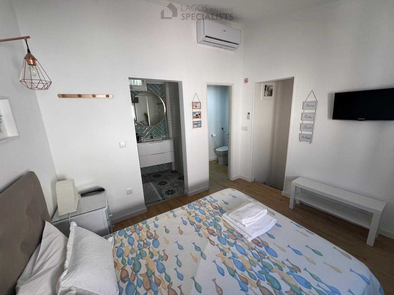 Master bedroom with built-in closets, TV and large windows – renovated 1-bed house in Lagos