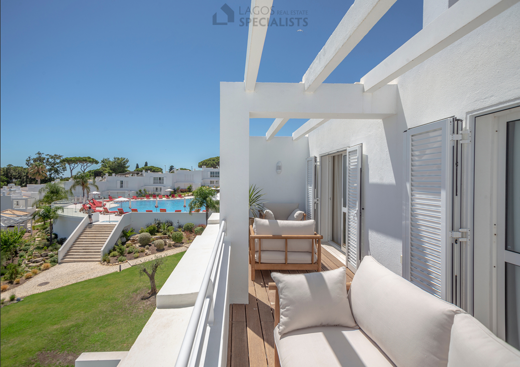 Pool view from private terrace with outdoor sofa at ocean front resort in Olhos d’Água