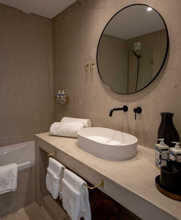 Contemporary bathroom with round mirror and natural finishes in Algarve apartment