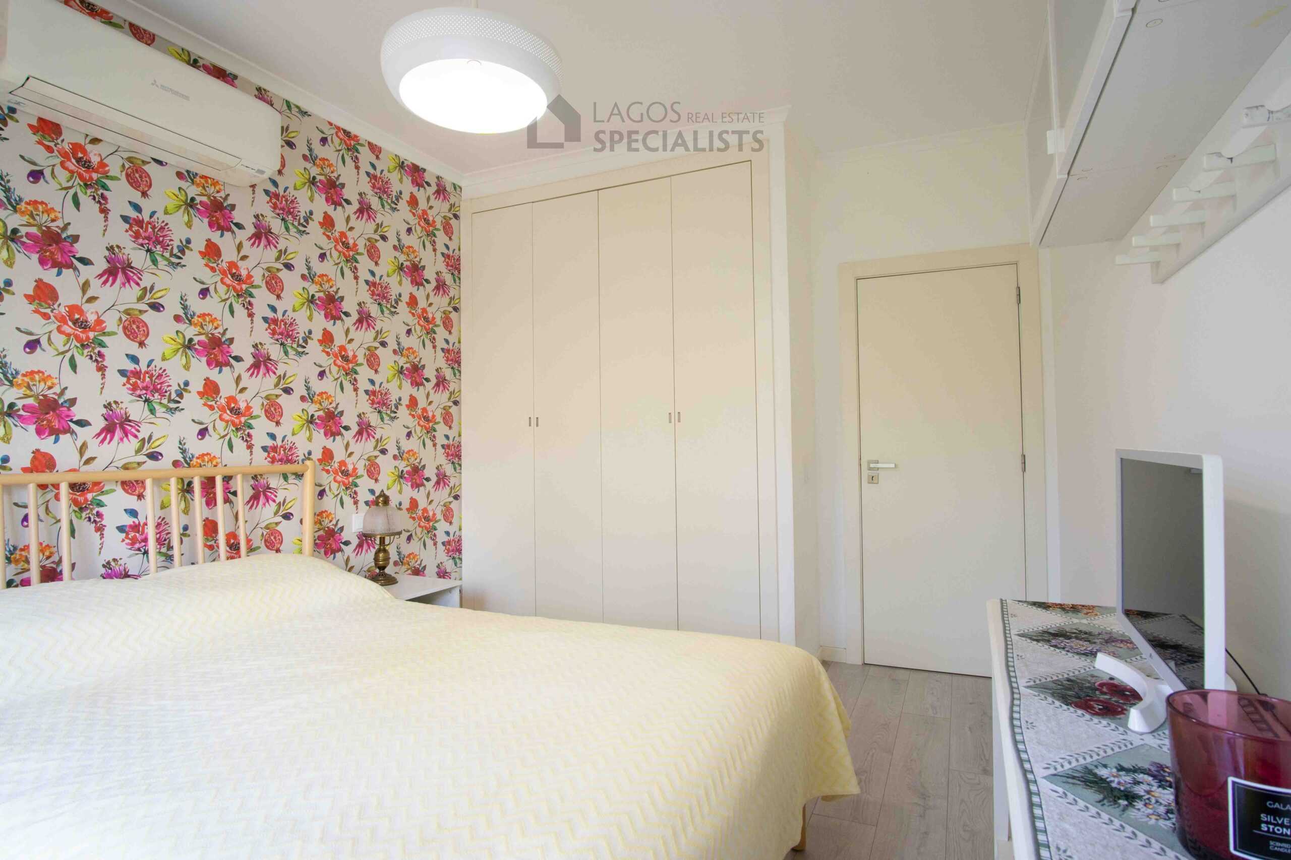 Well-proportioned bedroom with built-in wardrobes, floral feature wall, air conditioning, and soft natural light in Lagos apartment