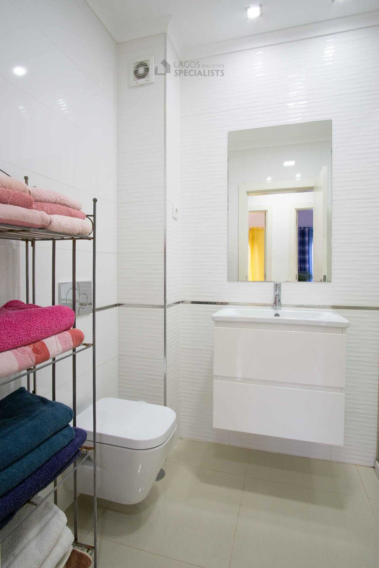Contemporary bathroom with walk-in shower, wall-hung vanity, mirror, and neatly arranged towels in Lagos apartment