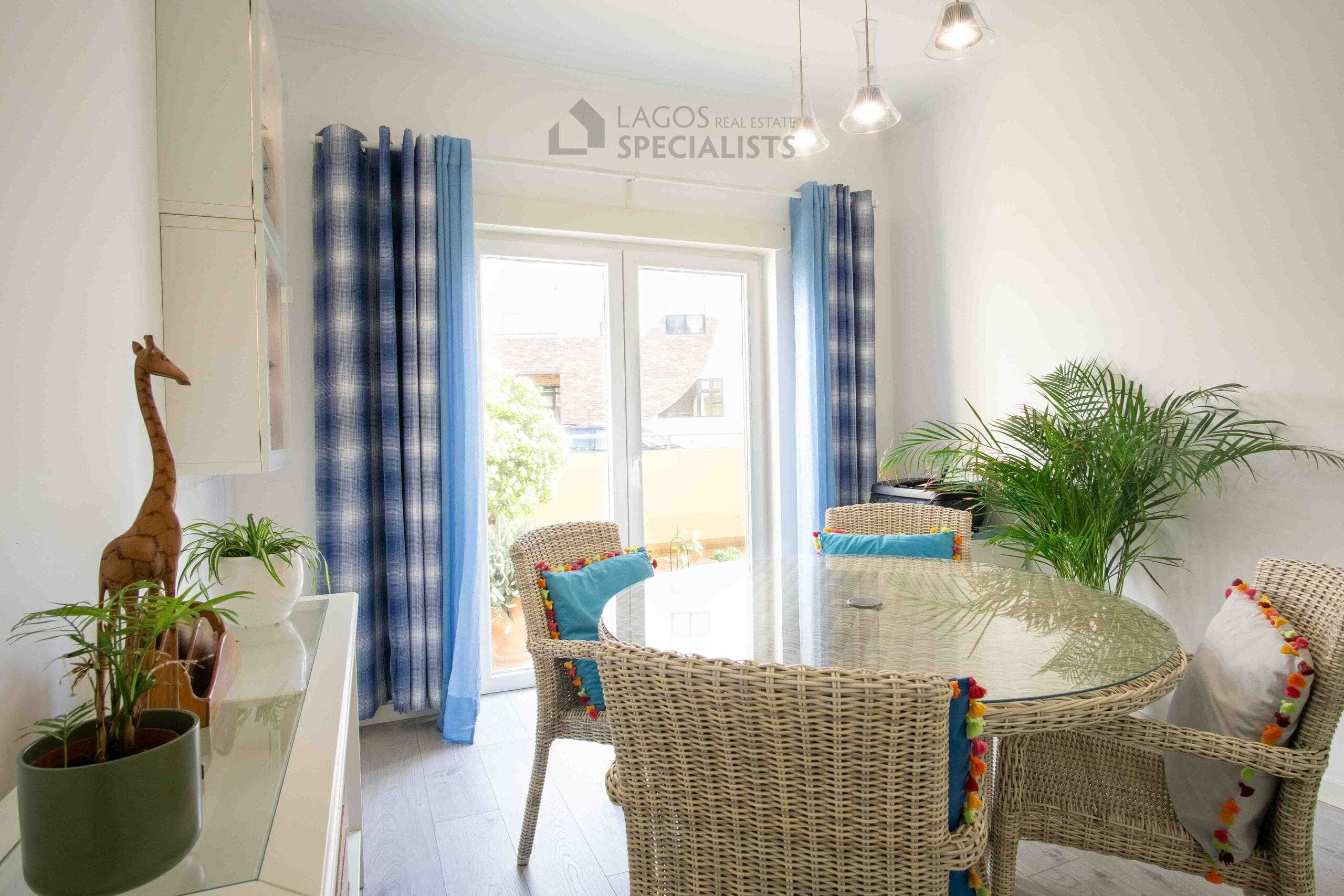 Stylish dining space with natural textures, indoor plants, and large sliding doors creating a relaxed atmosphere in Lagos apartment