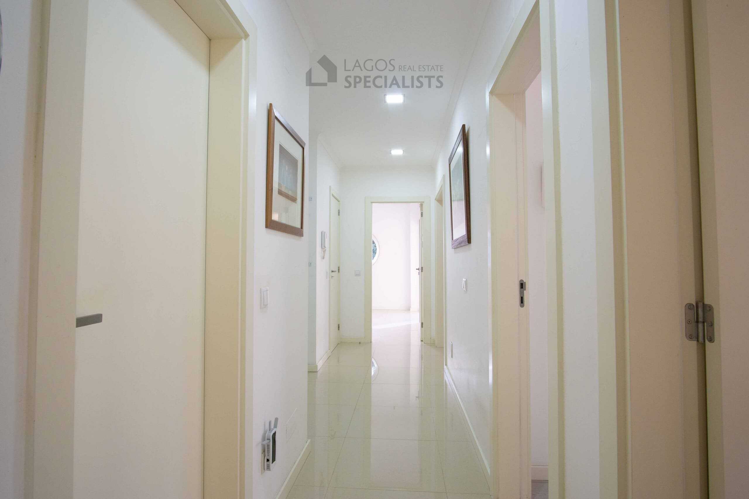Bright entrance hallway in a modern Lagos apartment with white tiled floors, recessed lighting, and access to bedrooms and living areas