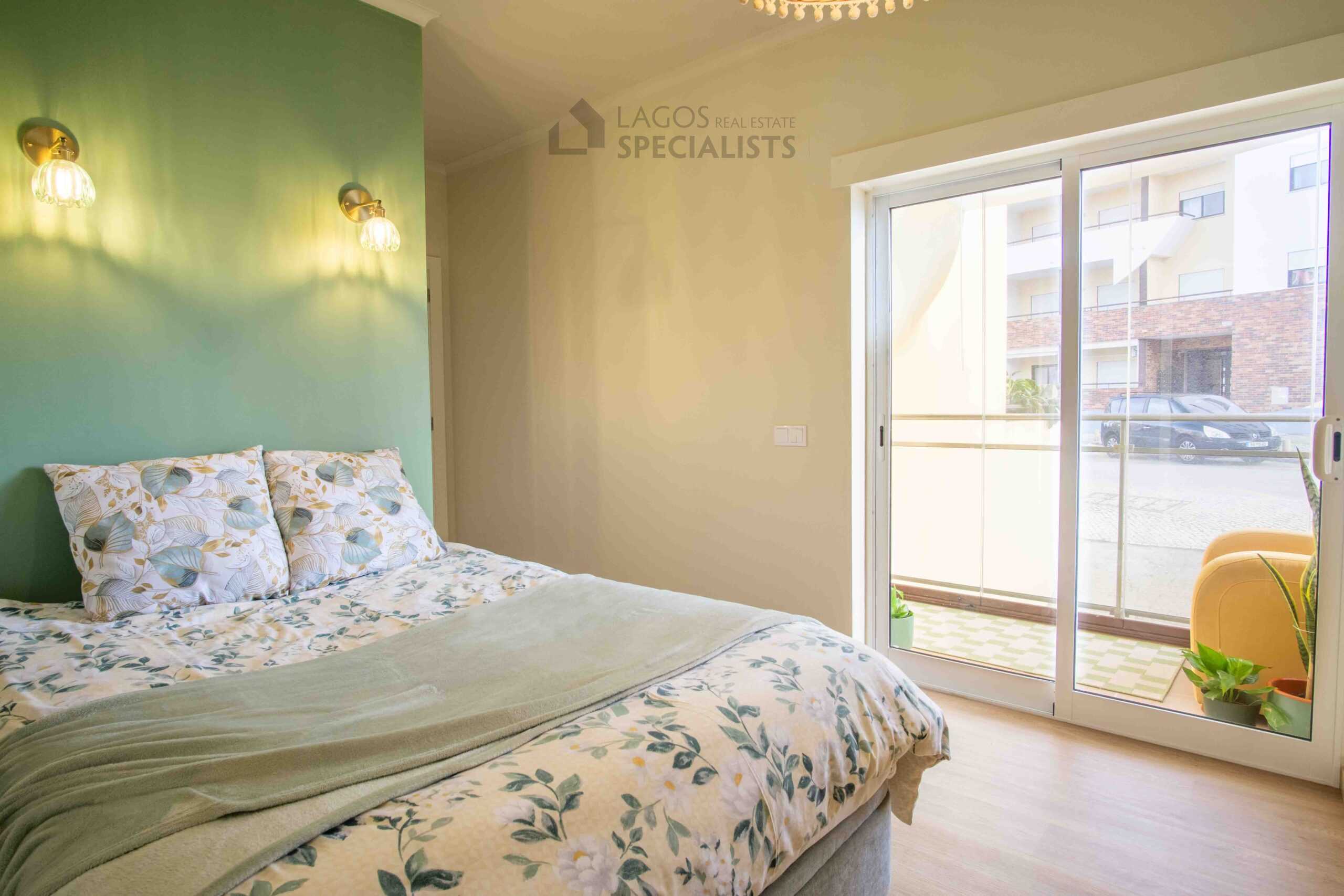 Bright bedroom with green feature wall, double bed and balcony access in modern Lagos apartment