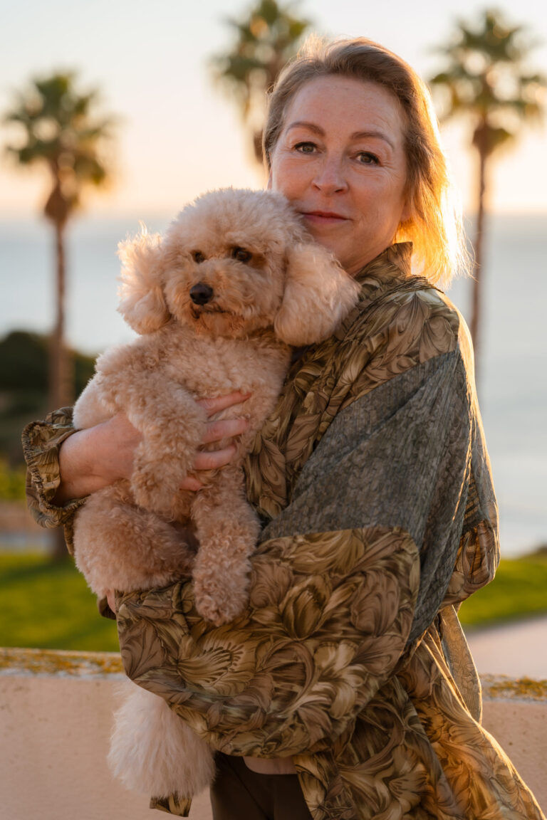 Natasha Hunt and dog Dolly on Algarve real estate tips with palm trees and coastal background