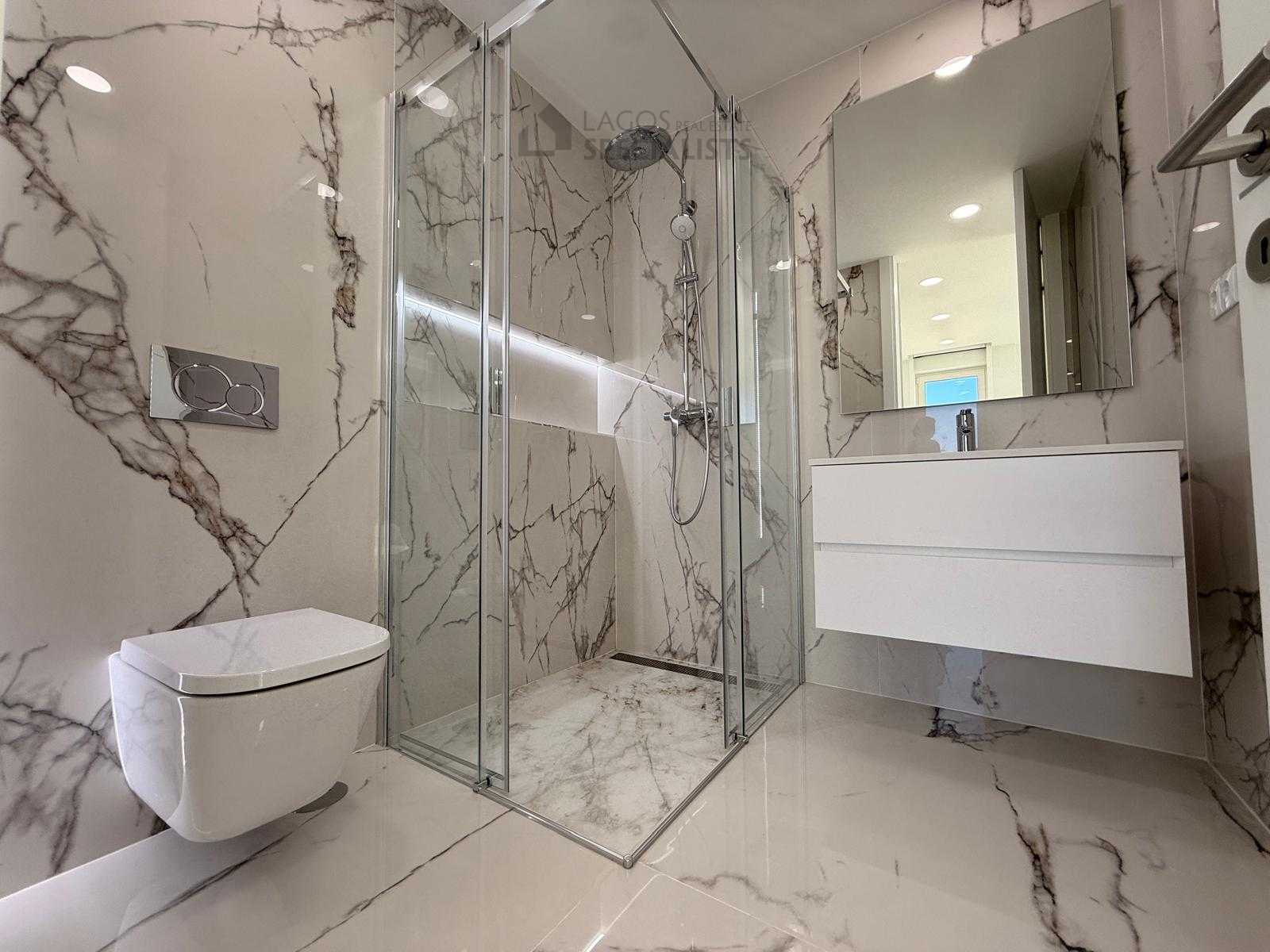 Glass walk-in shower with marble finish tiles in Lagos Portugal apartment